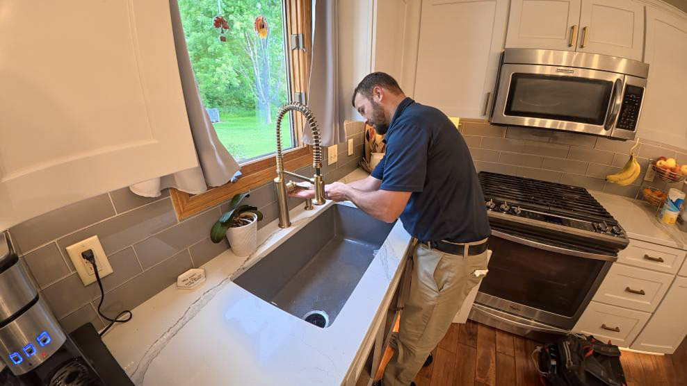 A Thrasher Service plumber fixes a broken kitchen faucet in a Des Moines home.